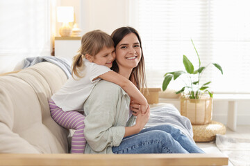 Happy mother and her cute daughter on sofa at home