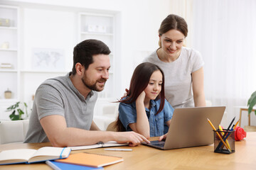 Obraz premium Parents helping their daughter with homework at wooden table indoors