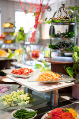 Fresh and colorful salad counter at a hotel buffet featuring a variety of vegetables, toppings, and dressings, neatly arranged for a healthy dining experience.

