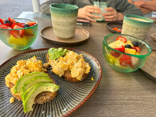Breakfast with avocado toast, scrambled eggs, fruit salad, healthy meal, fresh ingredients, brunch time, wholesome plate