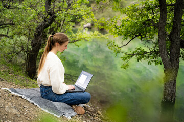 Young woman working on laptop pc computer with graphic design software outdoors wearing casual...