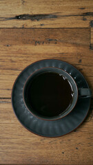 a glass of black coffee served on a wooden table