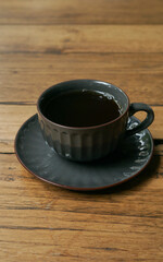 a glass of black coffee served on a wooden table