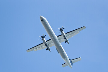 A large white airplane is flying through a clear blue sky