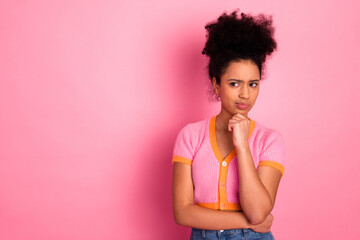 Cheerful girl in casual attire expressing thoughtful pose against a vibrant pink background,...