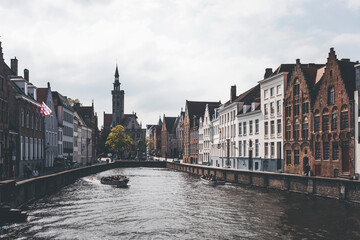view of the old town of brugge in belgium, and its canals, on a spring day. blue pastel atmosphere and cloudy sky
