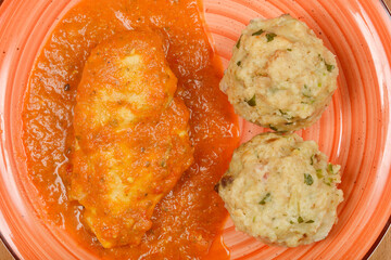Overhead shot shows a plate with chicken paprikash and two bread dumplings