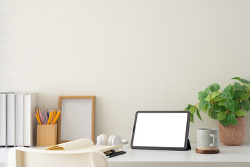 Minimal white desk featuring digital tablet with blank screen, notebook, and coffee mug, ready for design insertions.
