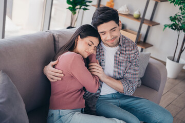 Obraz premium Young couple embracing affectionately on a cozy couch at home, enjoying leisure time together in a bright and stylish living room interior.