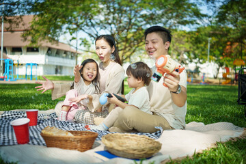 Happy family spending leisure time together while playing with bubbles in the park.