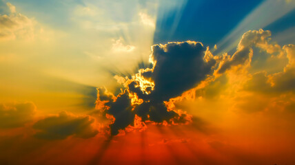 A dramatic sunset photograph with sunbeams piercing through golden and dark clouds.