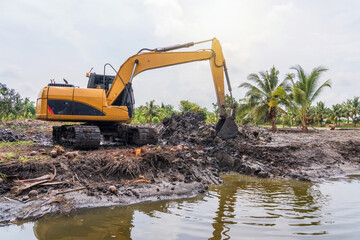 Construction work to adjust the area for agriculture. Excavator is working pipe laying and trench digging work in cultivation areas in lowlands Thailand.