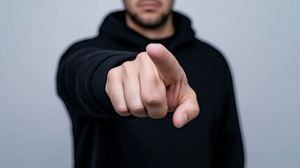 Man in black hoodie points directly forward, possibly indicating a person or thing in front of him.