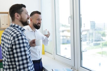 Fototapeta premium Colleagues looking out window during coffee break in office