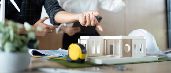 Obraz premium Sustainability in Engineering. Engineers discussing eco-friendly building model.