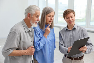Fototapeta premium Smiling real estate agent with clipboard working with couple at home