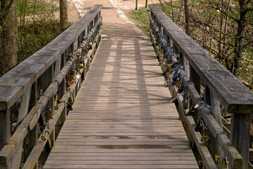 Old wooden bridge with iron locks on the fence, early spring.