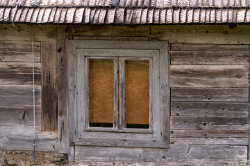 Old wooden window on the wooden wall of an old wooden house.