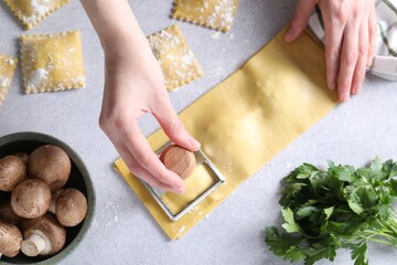 Woman cutting ravioli at light table, top view