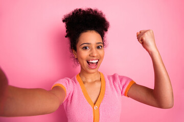 Young woman in casual trendy outfit celebrates enthusiastically in front of a vibrant pink...