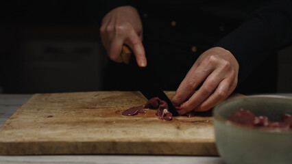 Chef Cutting Raw Chicken Liver on Wooden Board.
