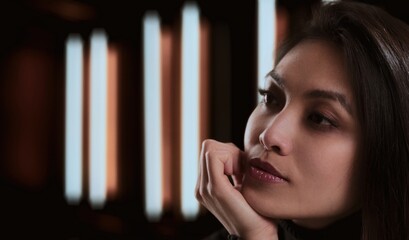 Woman thoughtfully gazing with blurred lights in the background