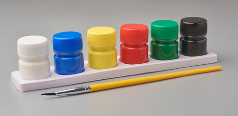 pack of colorful poster color bottles with yellow brush isolated gray background, mock-up template...
