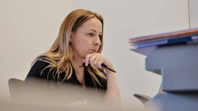 Thoughtful woman stares at screen in silence while mumbling in office setting