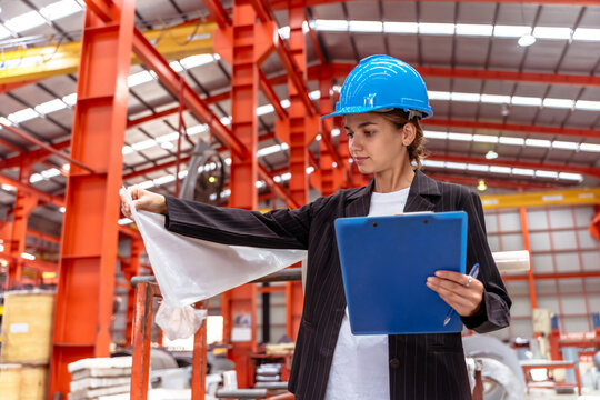 Young female Caucasian industrial worker holding clipboard checking quality manufacturing industry factory