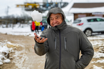 Senior Man Playing with Snow Outdoors in Winter