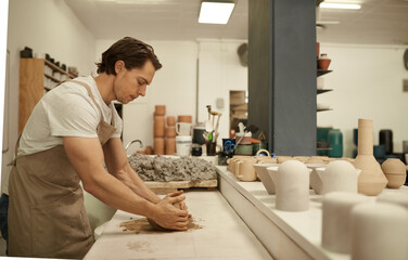 Ceramist working a piece of clay on a studio table