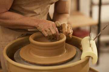 Pottery maker shaping a ball of clay turning on a wheel