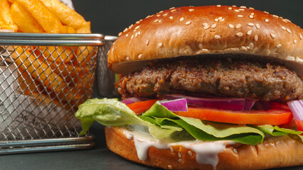 Fresh beef burger with Crispy French fries closeup on black background