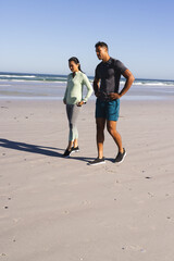 Fototapeta premium Walking on beach by ocean, couple exercising together in morning