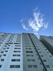High-rise building with windows on the sides with a bright blue sky background. low angle photo of a high-rise building