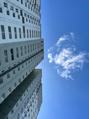 High-rise building with windows on the sides with a bright blue sky background. low angle photo of a high-rise building