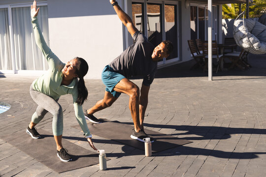 Couple exercising outdoors on yoga mats, stretching and enjoying morning workout
