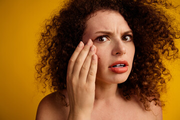 Confident young woman with natural curly hair expressing concern against a bright yellow background...
