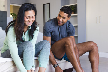 Couple getting ready for morning workout, smiling and tying shoelaces at home