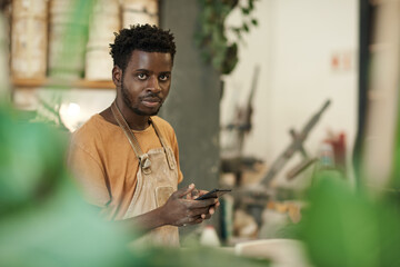 African ceramist using a phone while working in a pottery studio