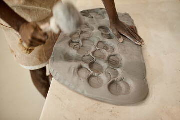 African ceramist flattening a piece of clay with a mallet