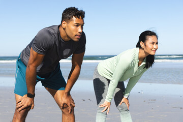 Fototapeta premium Fit couple taking break from jogging on beach, enjoying fresh ocean breeze