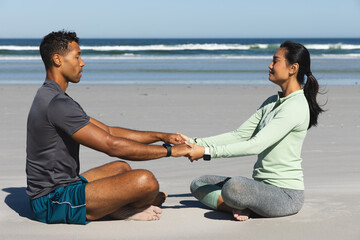 Fototapeta premium Couple sitting on beach holding hands, enjoying peaceful morning meditation together