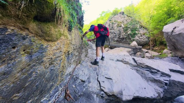 Climbing rocky pass between vertical walls on hiking route to Chorros de Fornos, Aragonese Pyrenees, adventure and extreme nature experience filmed in 4K UHD quality.
