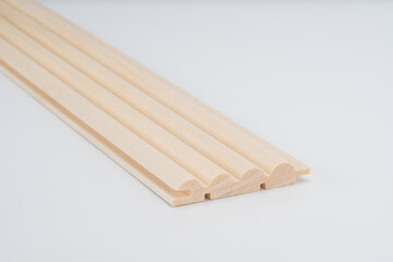 A close-up view of a decorative wooden moulding profile piece, isolated on a white background with clean lighting and copy space.