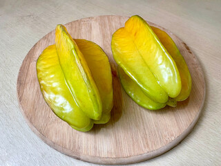 Ripe star fruit on a round wooden cutting board