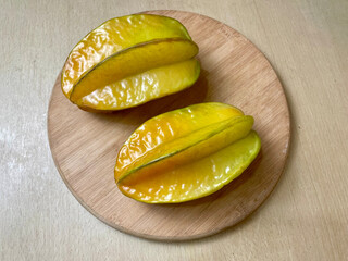 Ripe star fruit on a round wooden cutting board