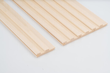 Lightwood grooved slats with stepped profiles, aligned on a white background. Suitable for decorative or acoustic interior panel applications..