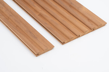 Brown wooden slats with stepped groove profiles, neatly arranged on a white surface. Ideal for wall paneling or acoustic cladding use..