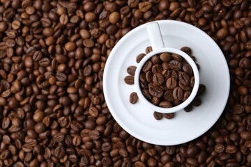 Cup and saucer on coffee beans, top view. Space for text